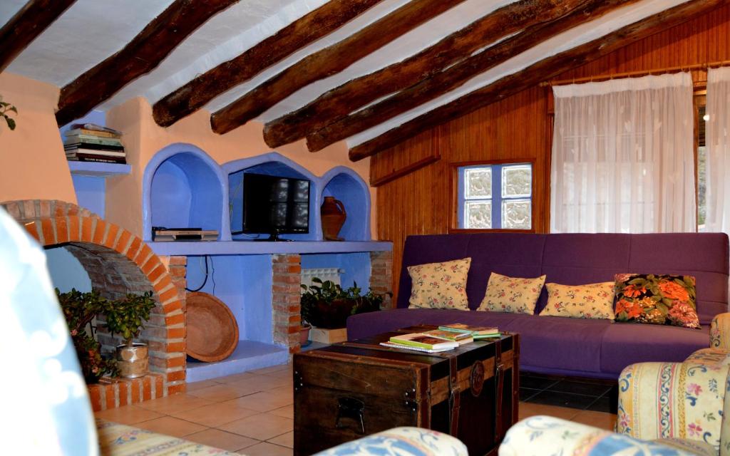 a living room with a purple couch and a fireplace at Casa Rural Manubles in Bijuesca