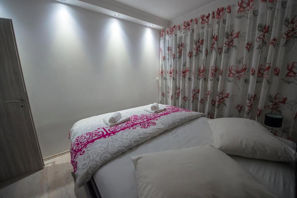 een slaapkamer met een bed met witte lakens en een gordijn bij Apartmani Marin in Split