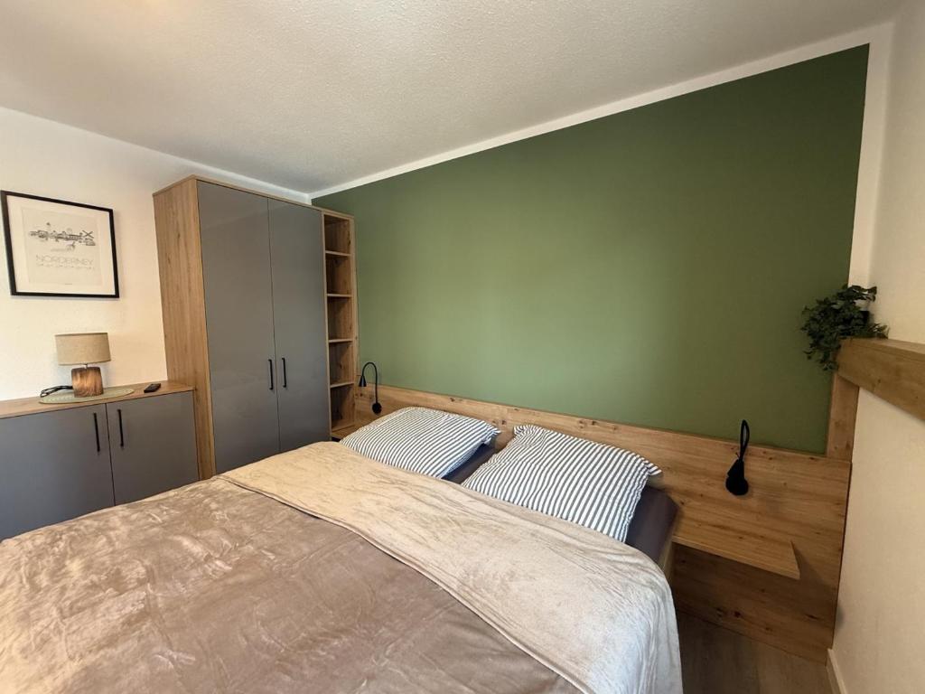 ein Schlafzimmer mit einem Bett und einer grünen Wand in der Unterkunft Schmidteinander in Norderney