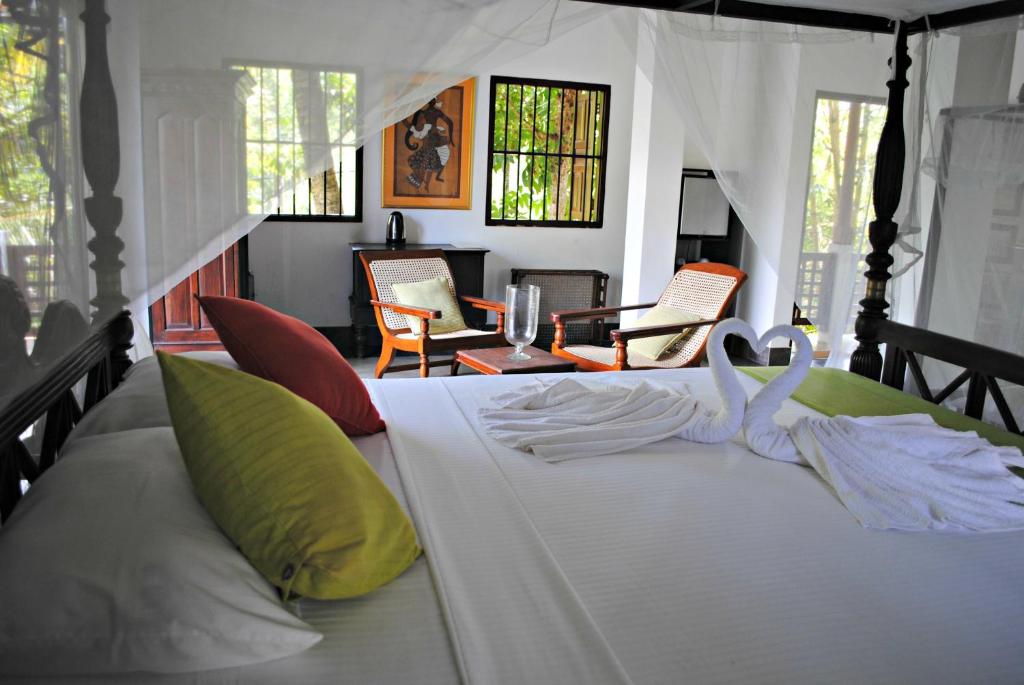 a bed in a room with chairs at Wasantha Garden Hotel Restaurant & Ayurvedic Treatment in Weligama