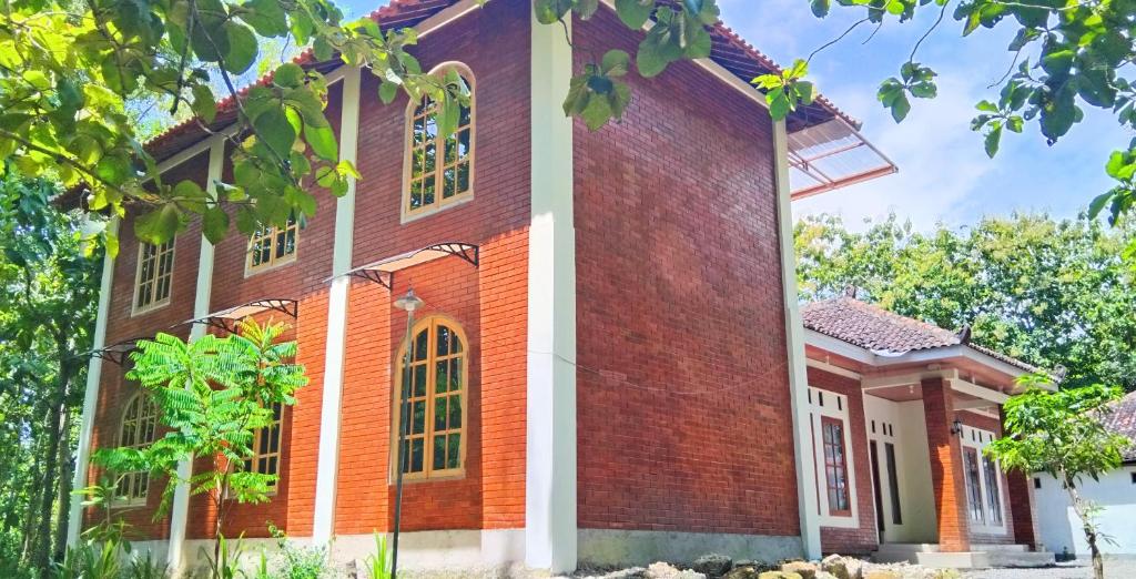 a red brick house with white columns at Amini Guest House in Jatiayu
