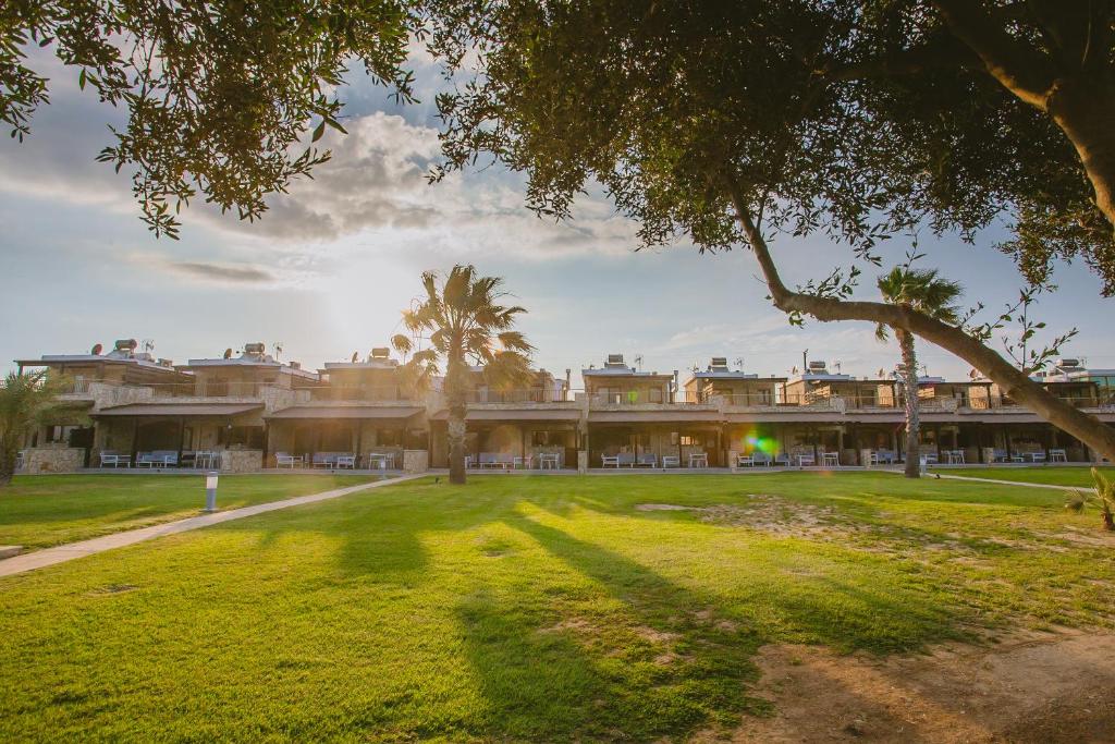 an exterior view of a building with a green yard at Elya Beach Luxury Suites in Ayios Theodhoros