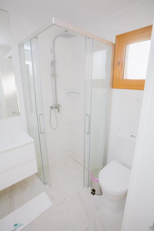 a white bathroom with a shower and a toilet at Elya Beach Luxury Suites in Ayios Theodhoros