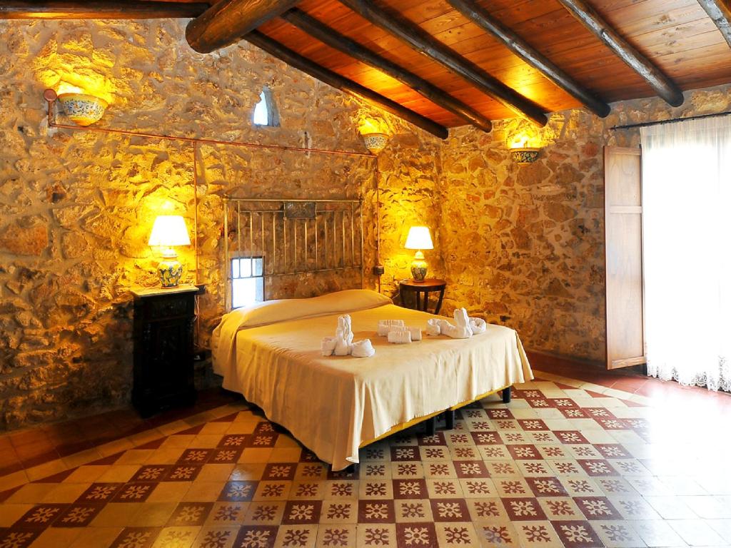 a bedroom with a large bed in a stone wall at Grand Hotel La Batia in Alcamo