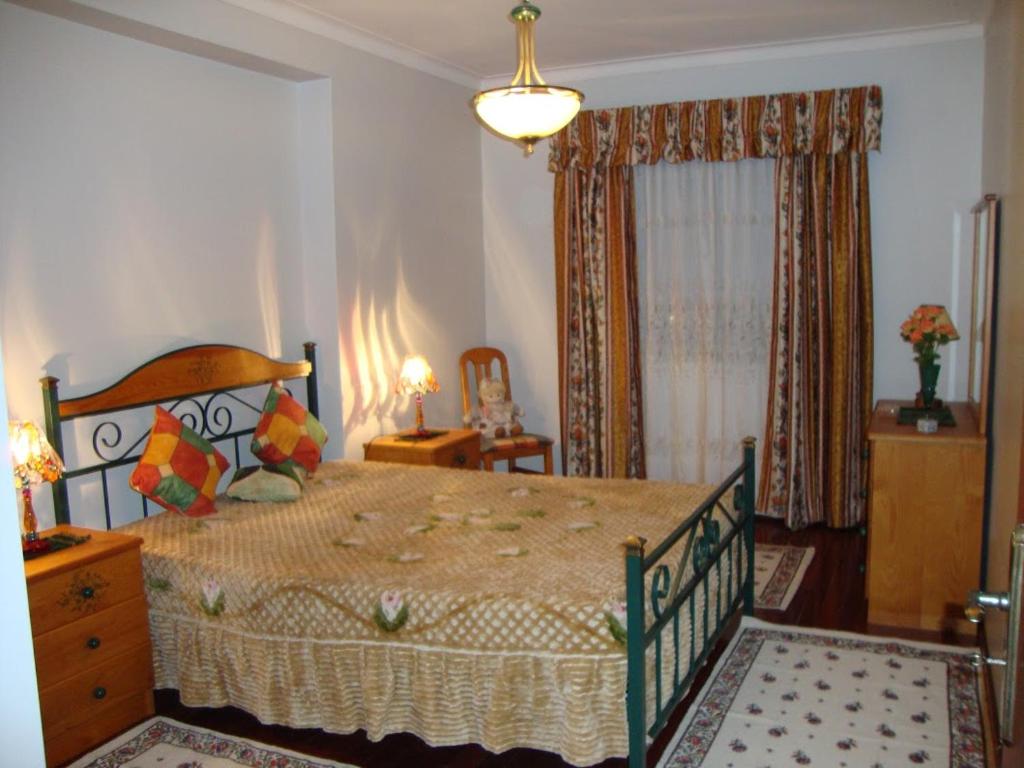 a bedroom with a large bed and a dresser at Apartamento Artur in Lousã
