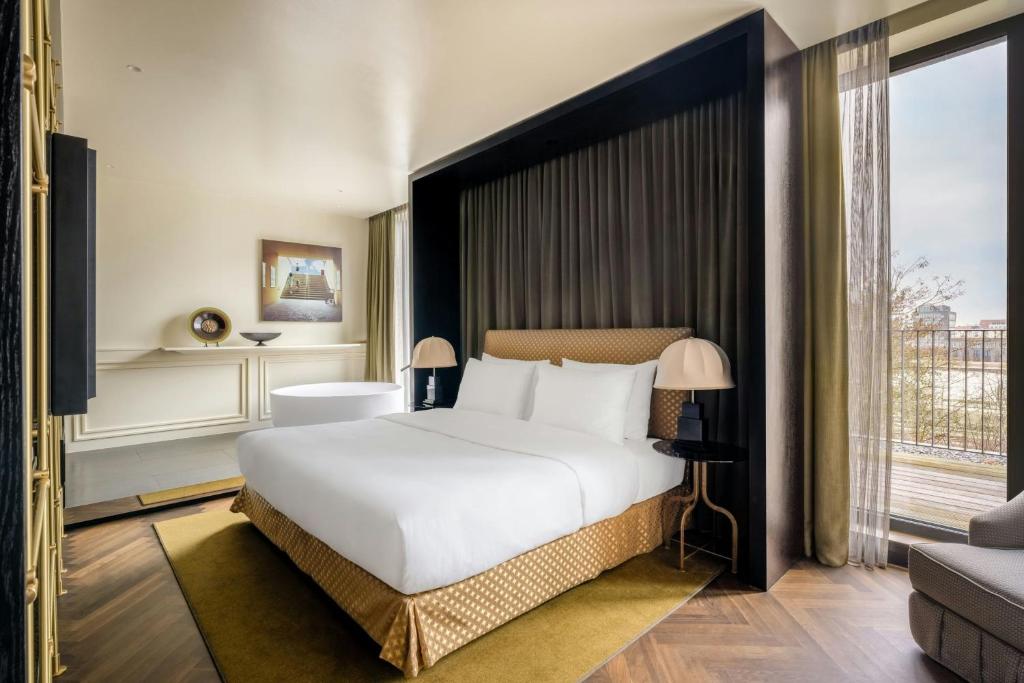 a bedroom with a large bed and a large window at The Dean Munich, Autograph Collection in Munich