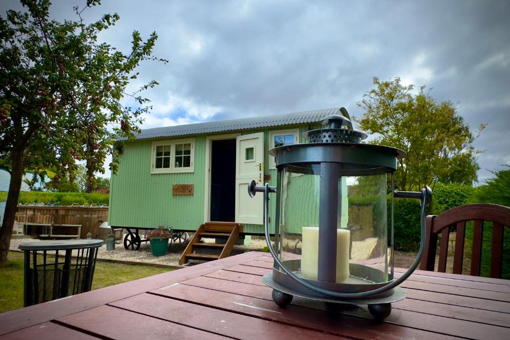 a lantern sitting on top of a wooden table with a house at Luxury Shepherds hut with wood fired hot tub on Lincolnshire Coast in Mablethorpe