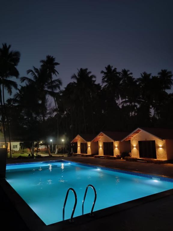 a swimming pool at night with lights around it at Palm Paradise Resort in Revadanda