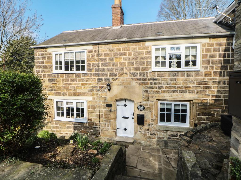 an old brick house with a white door at Lake Side Cottage in Wakefield