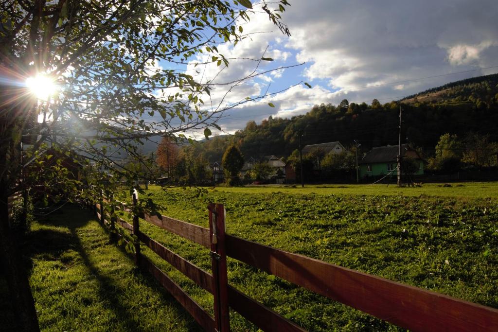 Una recinzione in un campo con il sole dietro di essa di Faina House a Jaremče