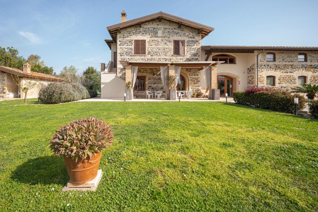 a large stone house with a potted plant in the yard at Casale Elisa Country Hotel in Ladispoli