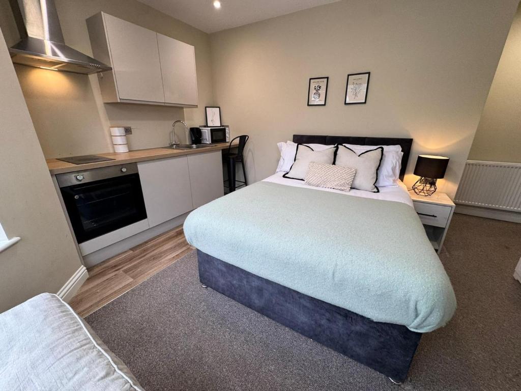 a bedroom with a large bed and a kitchen at Curzon St Aparthotel in Derby