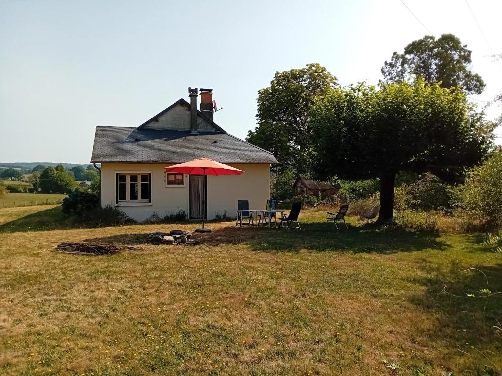 a small house with a red umbrella in a field at Petite Perle Parinet in La Croisille-sur-Briance