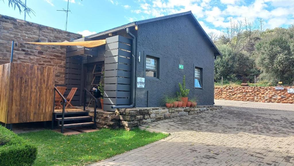 a small black house with a stone wall at A Little Guesthouse in Bloemfontein