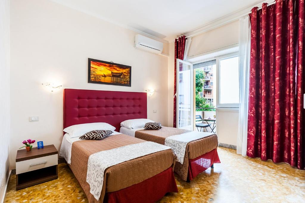 ローマにあるVatican Golden Roomsのベッド2台と赤いヘッドボードが備わるホテルルームです。