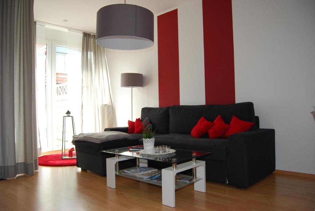 ein Wohnzimmer mit einem schwarzen Sofa und roten Kissen in der Unterkunft Detailverliebt in Dornumersiel in Dornum