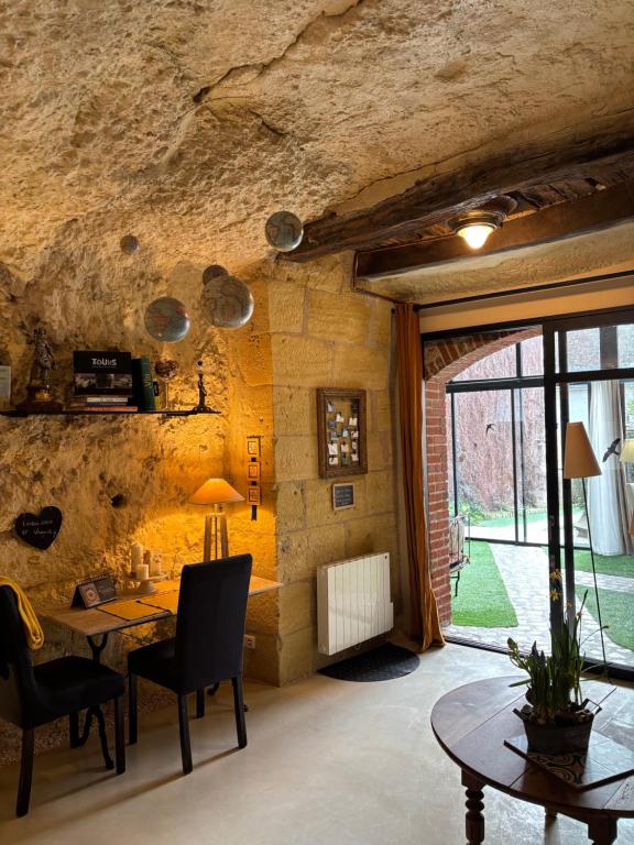 a dining room with a table and a stone wall at Troglodytes "Loire Sauvage" in Rochecorbon
