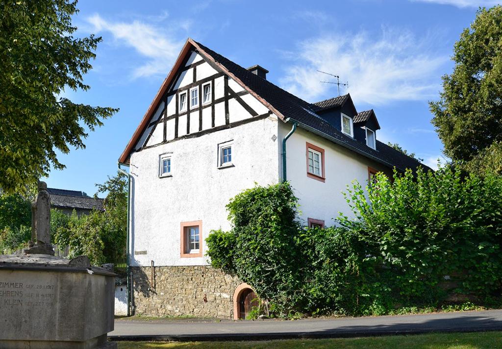 een groot wit huis met een zwart dak bij Zum Pinken Schaf in Ahrdorf