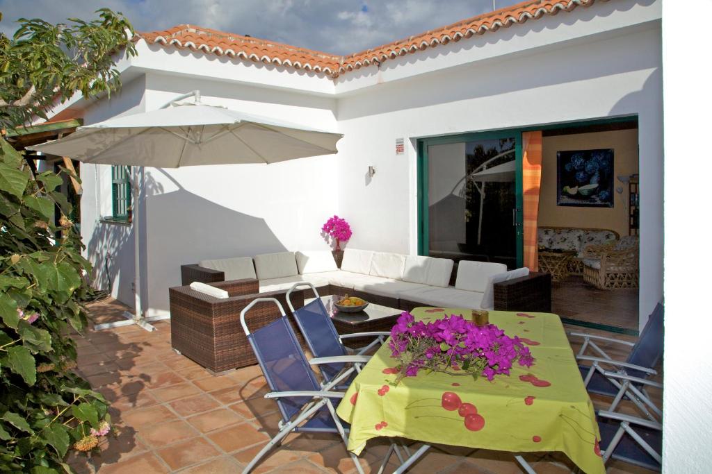 een patio met een tafel en stoelen en een parasol bij Casa Finca Avocado in Los Llanos de Aridane
