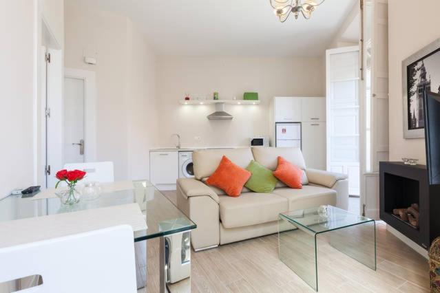 sala de estar con sofá y mesa de cristal en Apartamento Trajano, en Sevilla