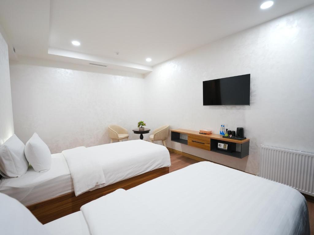 a hotel room with two beds and a flat screen tv at Premiere Hotel Tashkent Pool&Spa in Tashkent