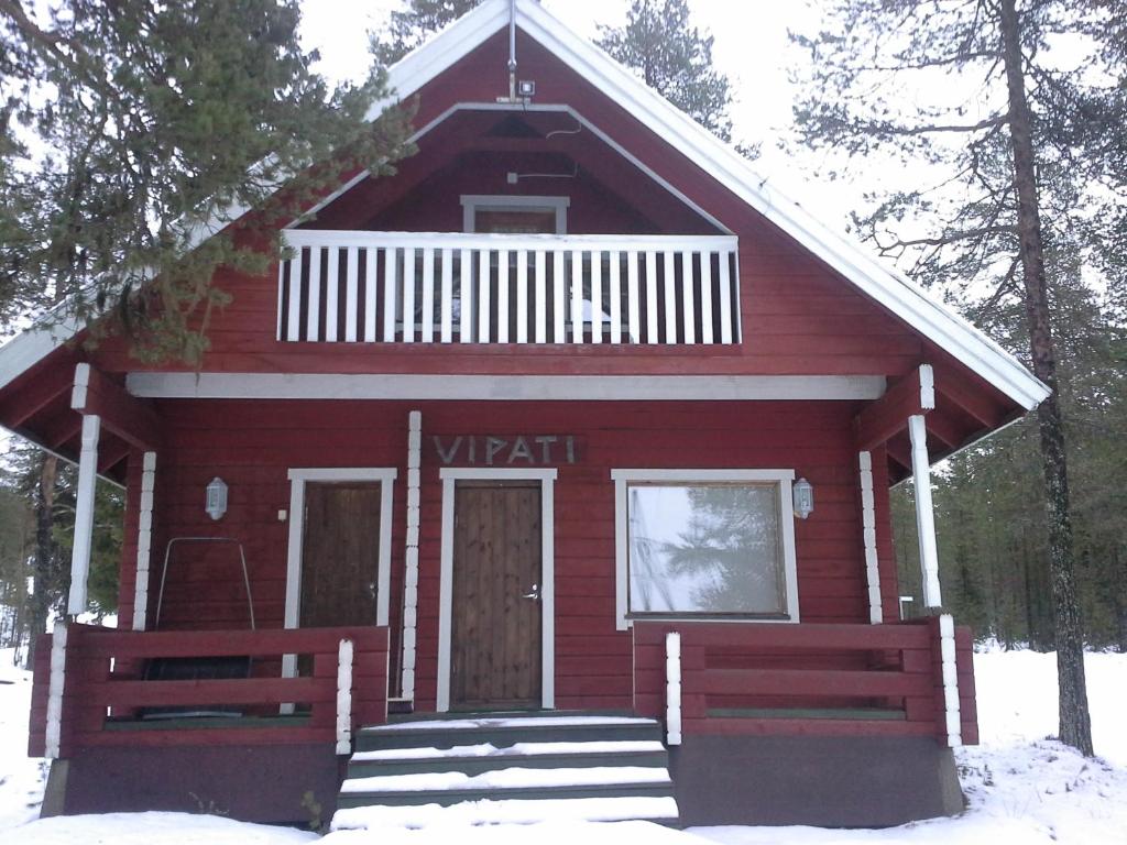 a red house with a porch and stairs in the snow at Vipati Cottage in Ylitornio