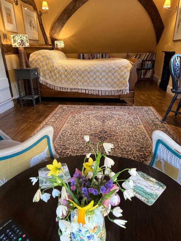 a room with a table with a vase of flowers at Under The Thatch at Rose House in Iwerne Minster