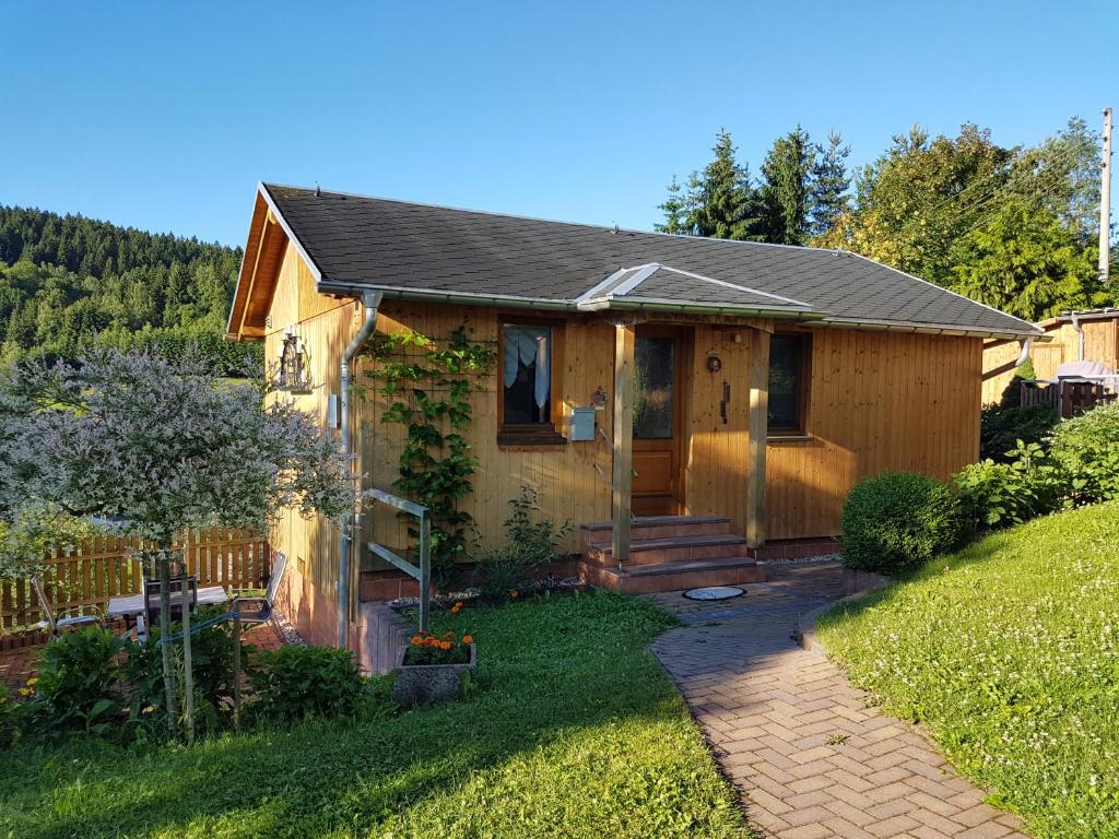 a small yellow house with a porch and a yard at Haus Talsperreneck in Stützengrün