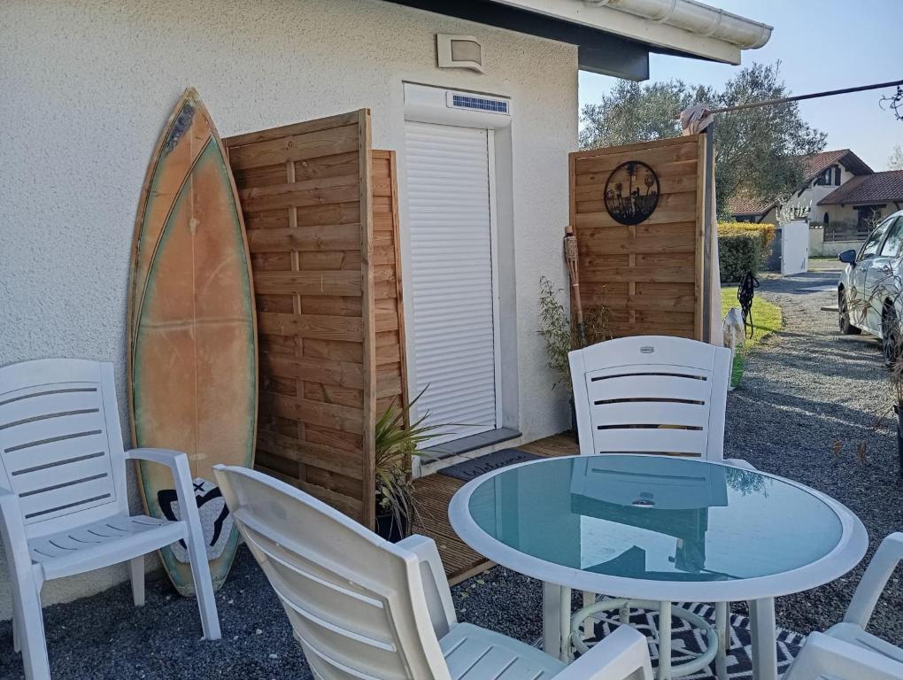 a table and chairs and a surfboard next to a house at T2 Charmant et calme in Andernos-les-Bains