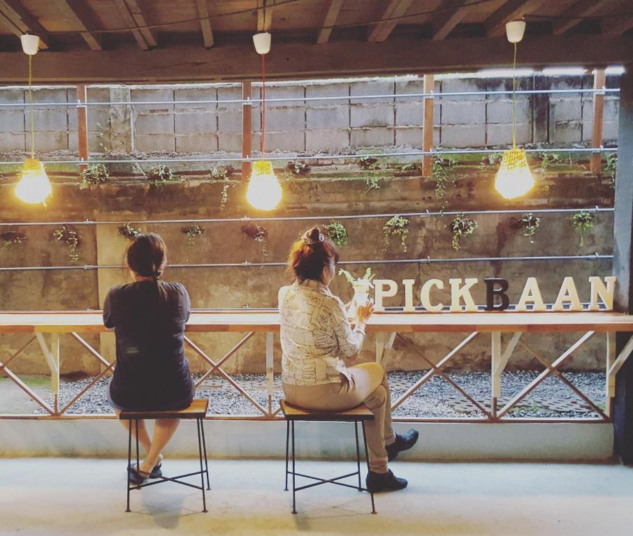 two women sitting on chairs looking out of a pick barn window at Pickbaan in Lamphun