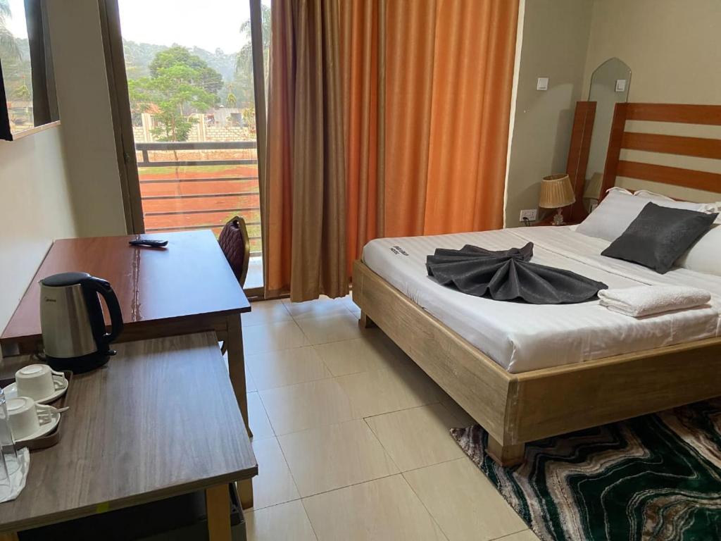 a bedroom with a bed and a table and a desk at Spark Africa Hotel in Jinja