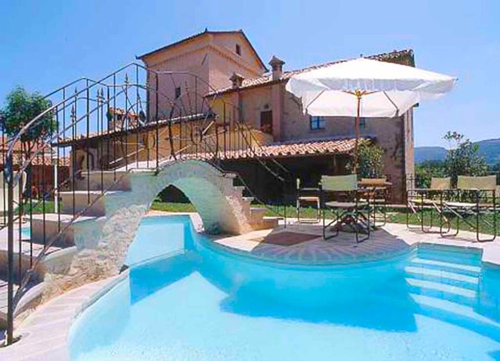 a swimming pool with an umbrella and a house at Monastery Birbino in Le Ville