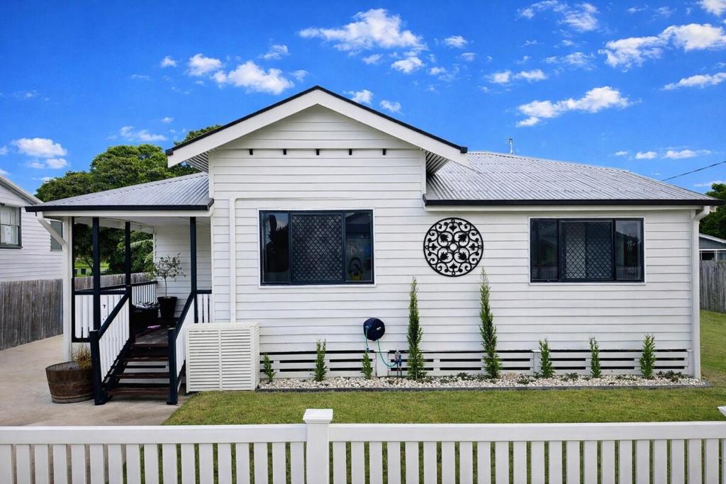 a white house with a fence in front of it at North Hamptons Retreat in Bundaberg