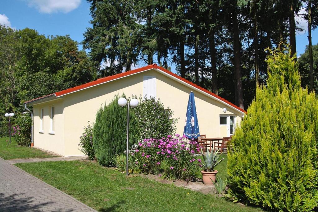 a small white building with a bench and flowers at Ferienhaus Eldeblick direkt am Eldeufer in Parchim in Parchim