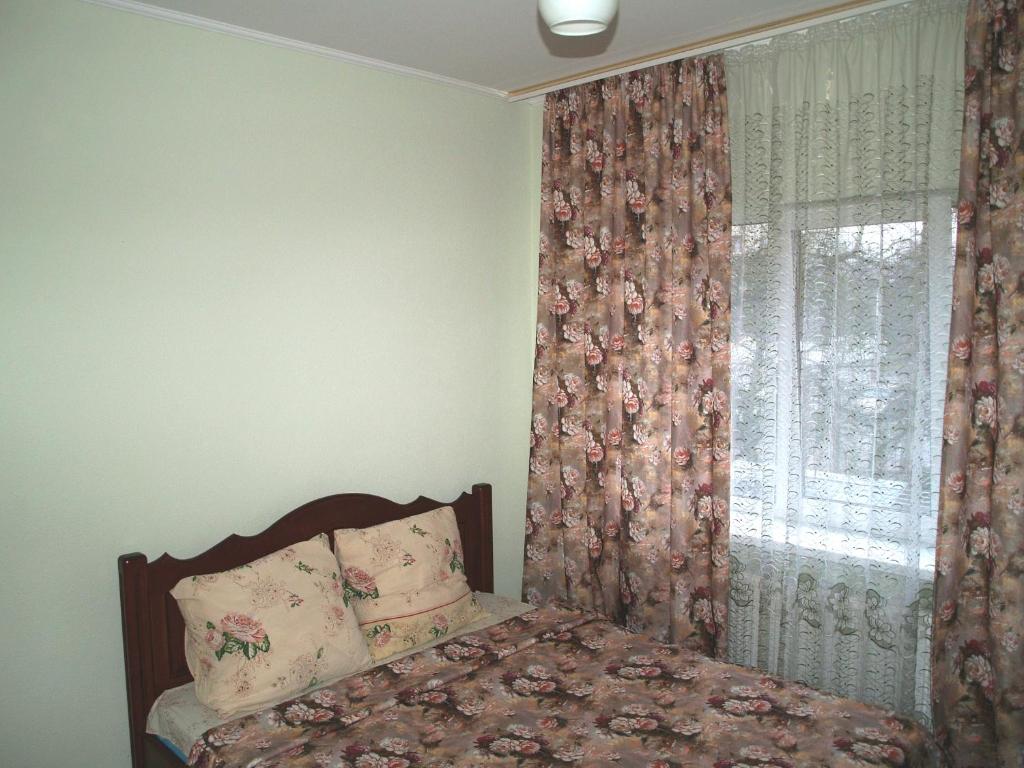 sypialnia z łóżkiem i oknem z zasłonami w obiekcie Apartament Sanitarna 17 w Lwowie