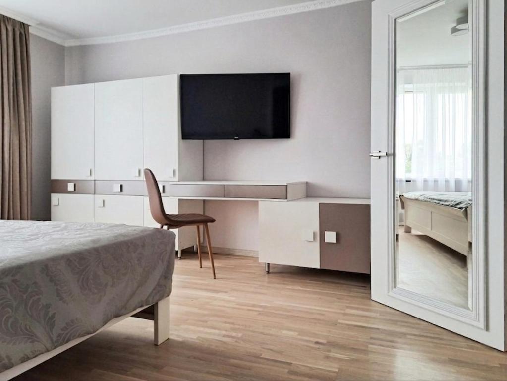 a bedroom with a bed and a desk and a mirror at White Home & Garden in Klaipėda