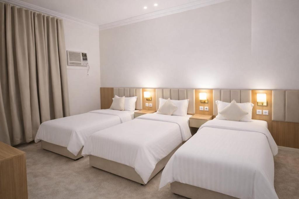 three beds in a hotel room with white sheets at Smo Hail سمو حائل in Hail