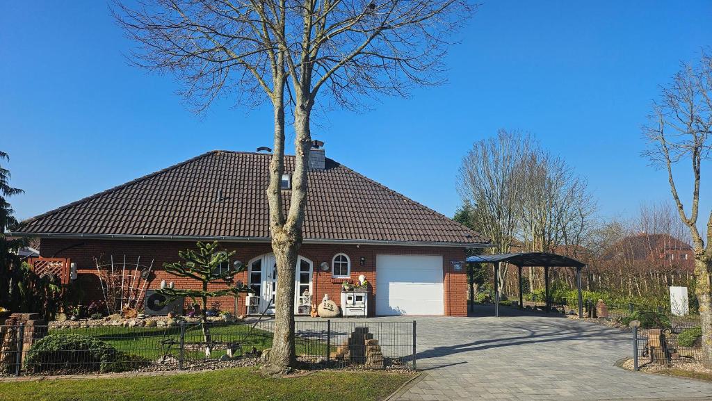 a house with a tree in front of it at Ferienhaus Gerda in Osteel