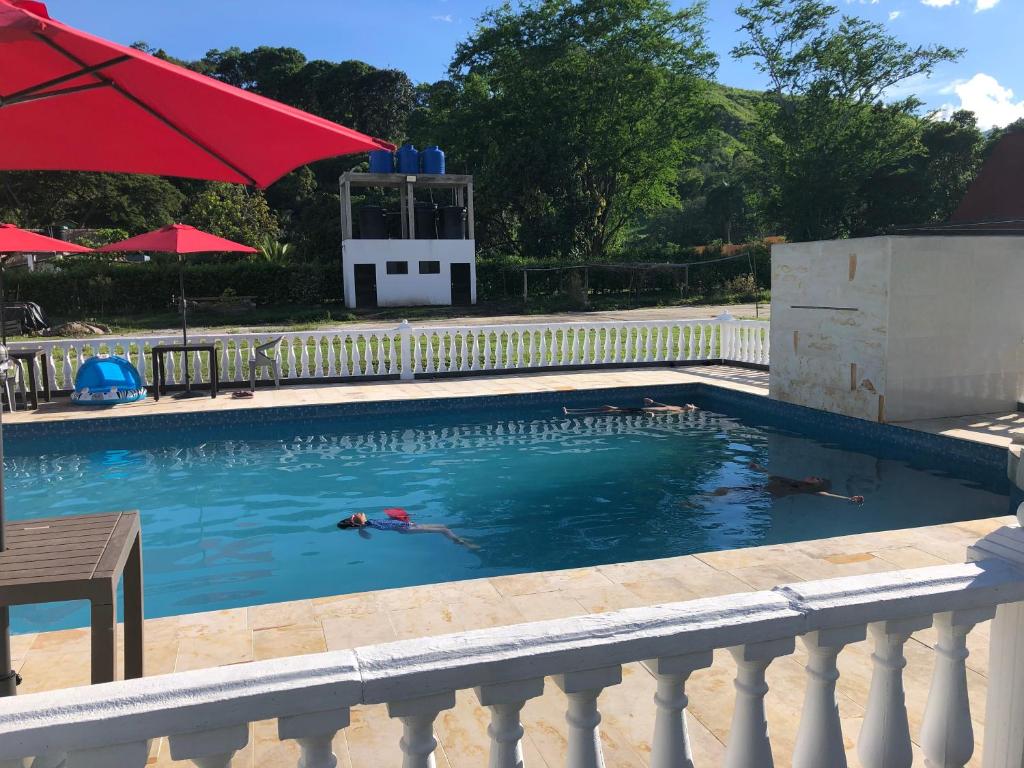 a person swimming in a pool with a red umbrella at Shaddai Villeta Centro Ecoturistico in Villeta