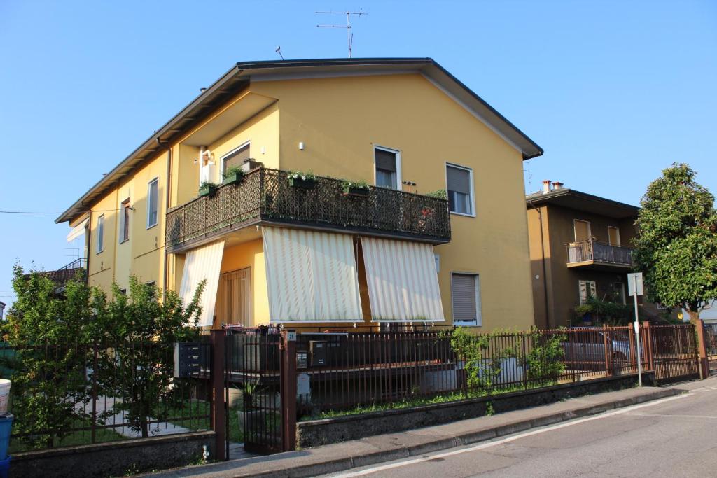a yellow house with a balcony on a street at Casa Nulfa in Sommacampagna