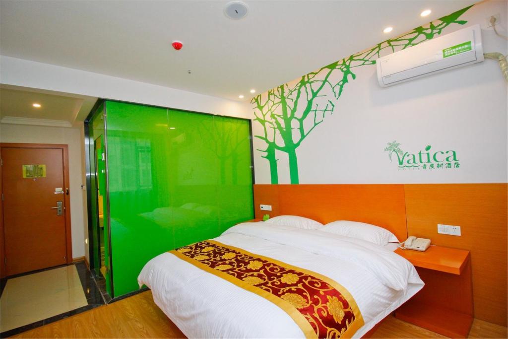 a bedroom with a bed with a green wall at GreenTree Hospitality Group Ltd Vatica Jiuquan West Han Shengsheng Shengshi Hotel in Jiuquan