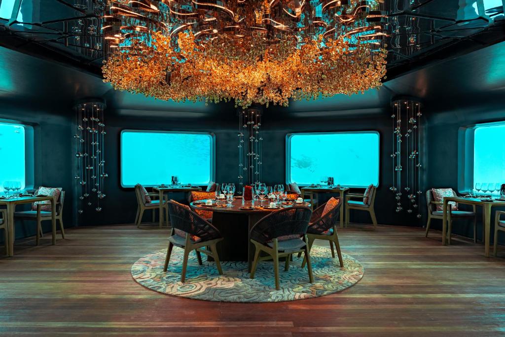 a dining room with a table and chairs and a chandelier at Meyyafushi Maldives - Premium All Inclusive in Lhaviyani Atoll