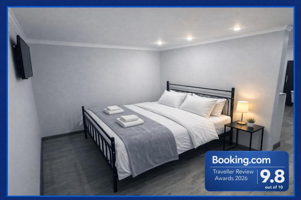 a bedroom with a bed with white sheets and a television at AIA Cozy Guest House 2 in Yerevan