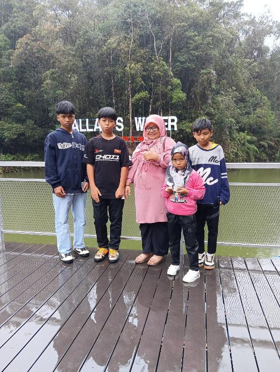 a woman and four children standing on a wooden deck at Homestay in Kulim