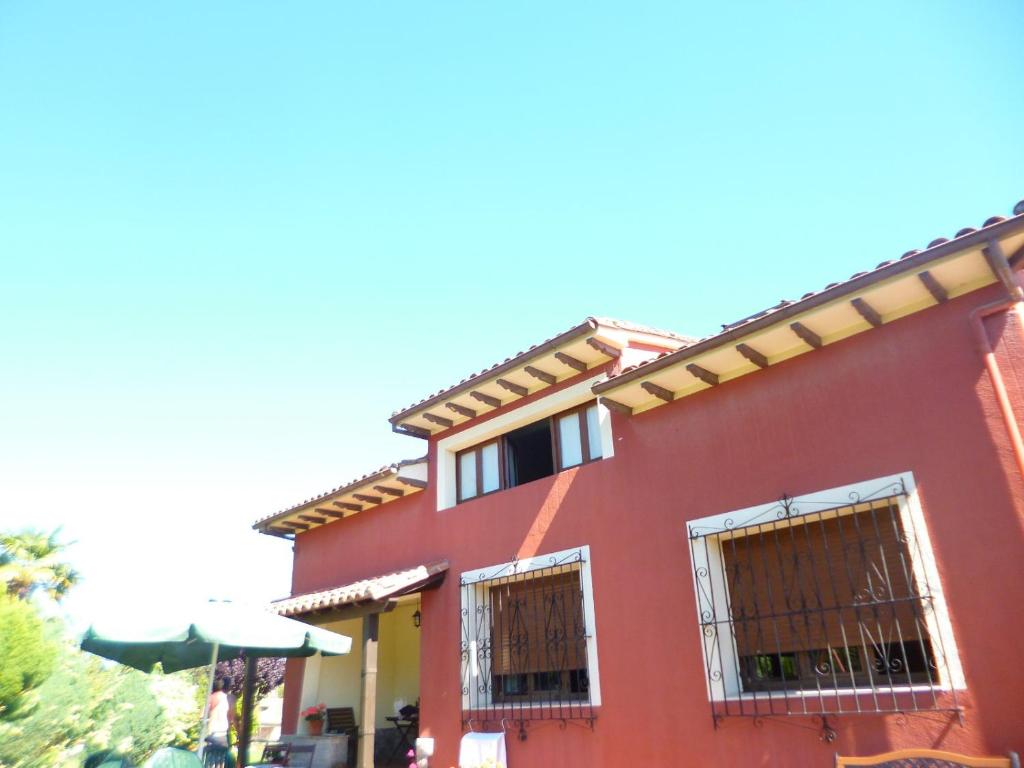 a red house with two windows and an umbrella at Los campos in Hontoria