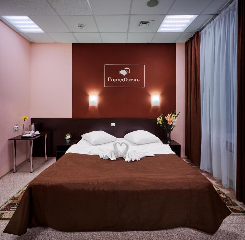 una camera d'albergo con un grande letto con lenzuola bianche di GorodOtel on Kievskiy a Mosca