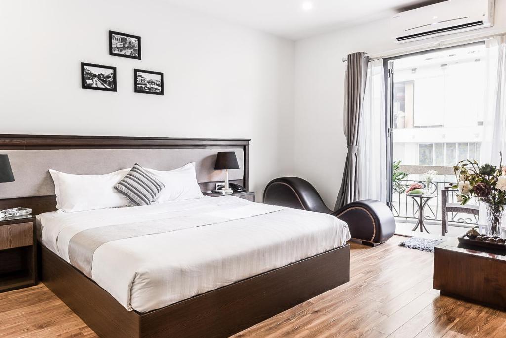 um quarto com uma cama grande e uma janela grande em Le Grand Hanoi Hotel - The Tryst em Hanói
