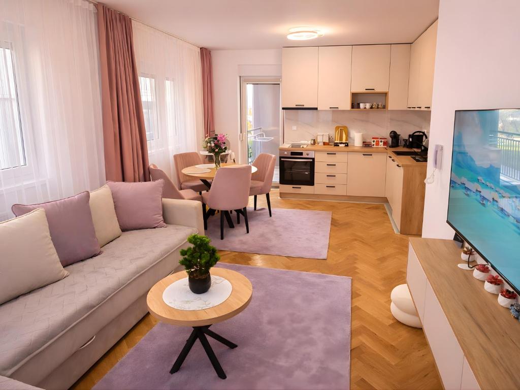 a living room with a couch and a table and a kitchen at Alma Apartment - Family Stay Across Aqua Park Raj in Vrnjačka Banja