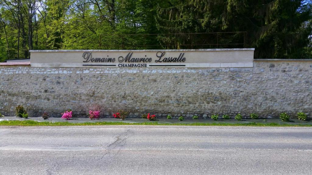 un panneau sur un mur de pierre avec des fleurs devant dans l'établissement Gîte Rilly-la-Montagne, à Rilly-la-Montagne
