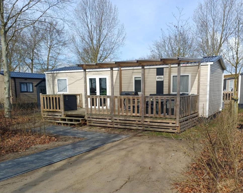 a mobile home with a large deck on a dirt road at Chalet Lauwersoog mét airco! in Lauwersoog